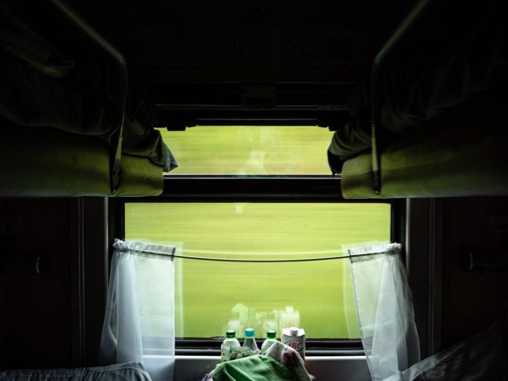 Green countryside rushing past the window of a sleeper train compartment